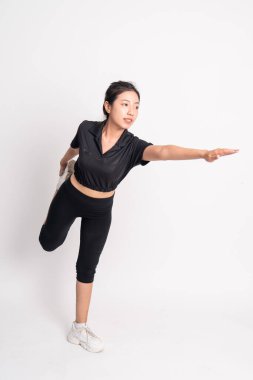 Ayakta duran kadın, arka planda dengeli bir şekilde bacak esnetiyor.