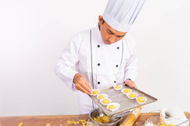 Erkek şef, izole edilmiş arka plandaki tepsinin üzerindeki kekin yapısallığını inceliyor.