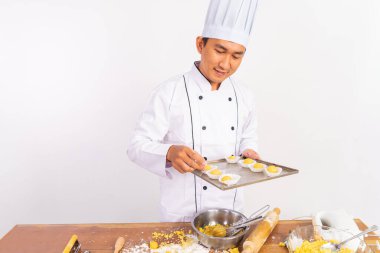 Erkek şef ayrı bir arka planda tepside kek donness gözlemliyor.