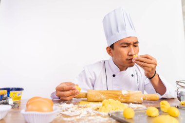 Ciddi erkek aşçı pasta kokusu alırken arka planda kek hamuru yapıyor.