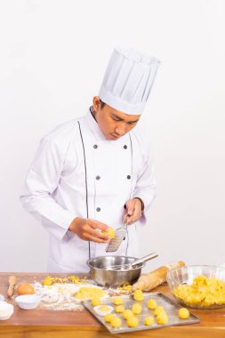 Erkek aşçı peyniri rendelerken ızgara peynirle mutfağın arka planında karıştırıyor.