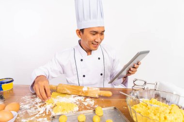 Gülümseyen erkek aşçı, tahta masada pasta yapıyor.