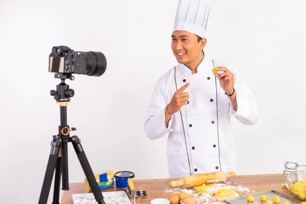 male chef food vlogger showing cake to camera while baking cake on table with isolated background