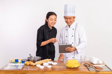 İki aşçı, yemek malzemelerini izole edilmiş arka planda bir masada işlemden geçirmeden önce bir ped kullanıyor.