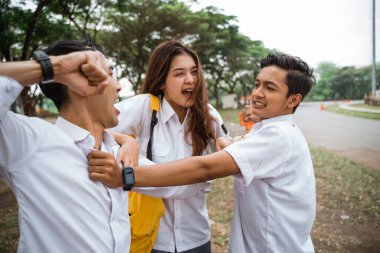 Üniformalı iki erkek öğrenci avluda bir kız tarafından ayrılmış.