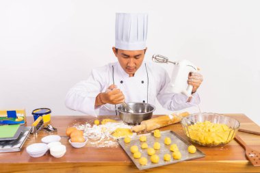 Erkek aşçı çırpma kabıyla karıştırıcıyı ayrı bir arka planda kullanıyor.