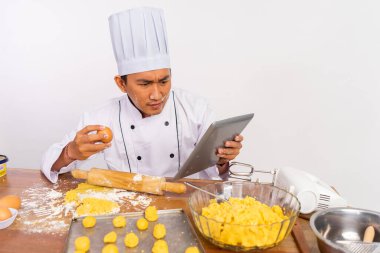 Kendini beğenmiş erkek aşçı ahşap masada kek pişirirken ped kullanıyor.