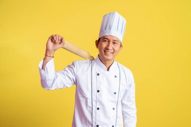 Şef ceketi giyen erkek şef izole edilmiş arka planda ahşap bir iğne tutuyor.