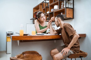 Bir adam yemek odasında karısıyla sorun yaşarken başını tutar.