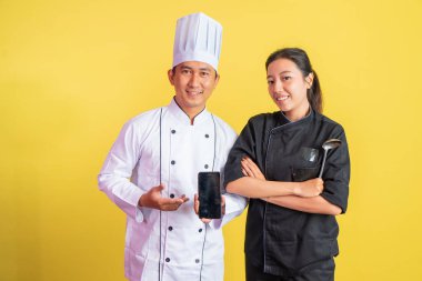 Erkek şef boş cep telefonu ekranı ve elleri çaprazlanmış kadın aşçıbaşı gösteriyor.