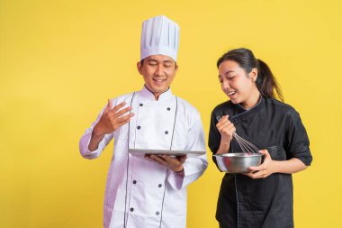 Hayali erkek aşçı tepside lezzetli ekmekler taşıyor ve kadın aşçı çırpıcıyla karıştırma kabını kullanıyor.