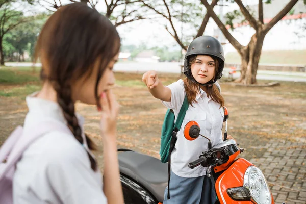 Student girl on motorbike pointing finger because of problem with student girl