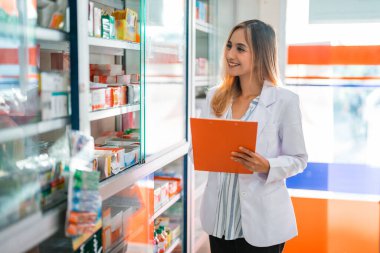 Eczanede pano ile çalışan üniformalı güzel bir eczacı kadın.