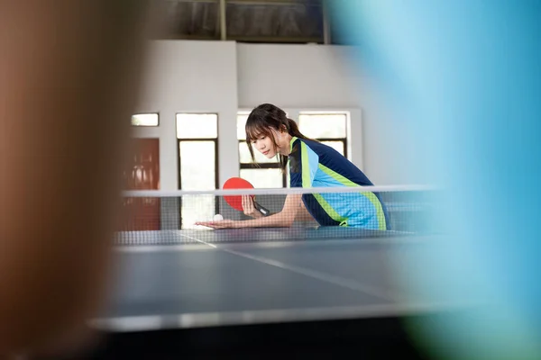 Female athlete holding paddle and ball while serving in table tennis