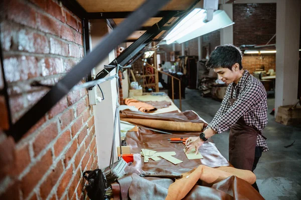 Young Asian male leather worker standing near table in his studio