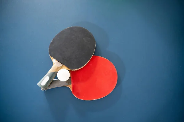 top view of two paddles with a ball on ping pong table