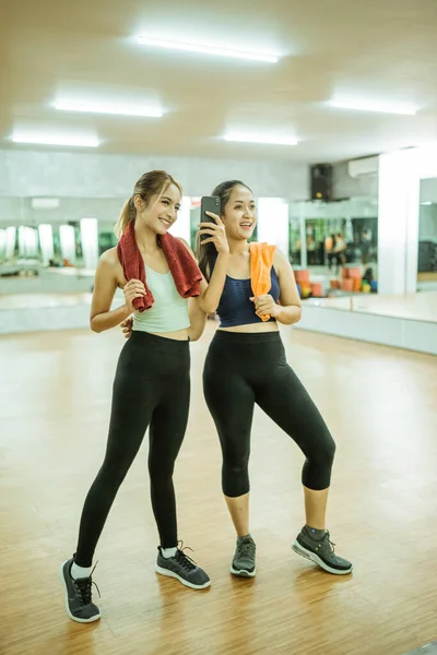 Two Sporty Women Standing Selfie Front Mirror Using Smartphone Camera — Foto Stock