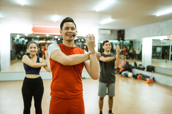 Male Instructor Leading Group Arm Muscle Stretching Movements Fitness Center —  Fotos de Stock
