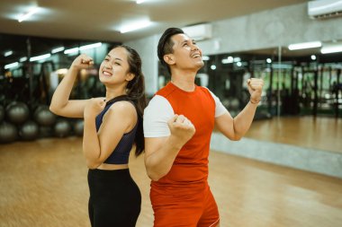 Heyecanlı kız ve erkek ellerini sıkarak spor salonunda dikiliyorlar.