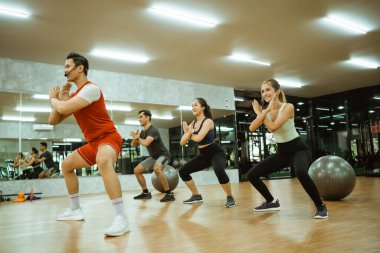 Erkek eğitmen, spor salonunda vücut savaşına katılanlarla el savunması yapıyor.