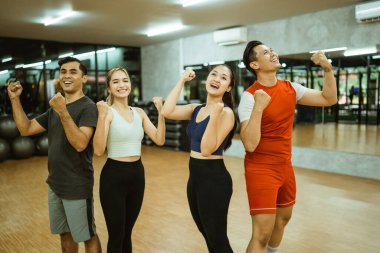 Spor giyim sektöründe yumruklarını sıkmış bir grup mutlu genç arkadaş.