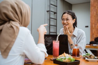 two girls enjoying a meal while discussing college assignments when they meet in a cafe
