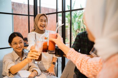 Two female college students in Lets toast with glasses gather in a cafe