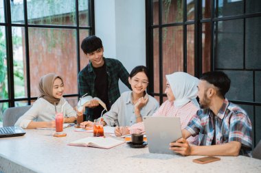 Asian young people discussing together in cafe with glass window background