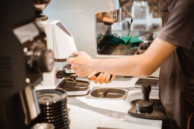 close up of barista hand using coffee grinding machine at barista table in cafe