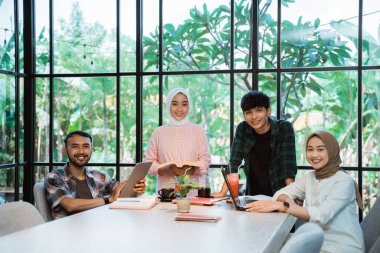 Asian young people smiling in indoor cafe with glass window background