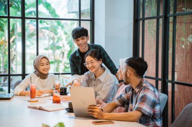 Asian young people meeting together in a cafe with glass windows in the background
