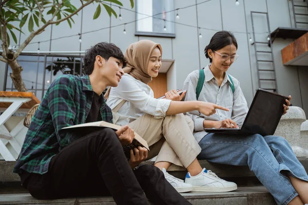 stock image Three young asian college students using laptops sitting on steps in cafe