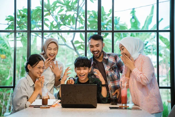 some young people are excited with surprise when they see a laptop in a cafe