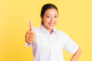 close up of teenage girl in high school uniform smiling with thumbs up on isolated background