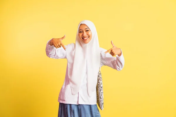 happy veiled high school student girl with two fingers pointing down on isolated background