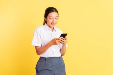girl in high school uniform typing message using mobile phone on isolated background