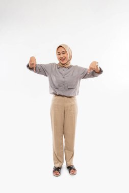 a beautiful woman with hijab standing facing forward with smile and pointing down on the white background