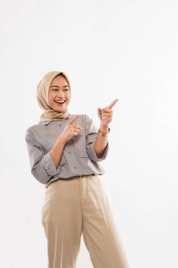 a beautiful woman with hijab standing with smile and excitedly pointing on the empty space at her left side on thw white background