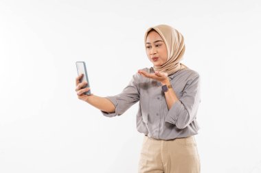 a beautiful woman with hijab standing raise her hand and blowing on her phone with the white background