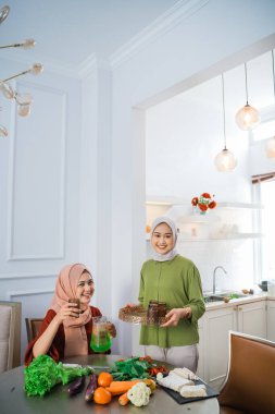 muslim woman serving drink for her friend and family at home having dinner together