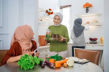 muslim woman serving drink for her friend and family at home having dinner together