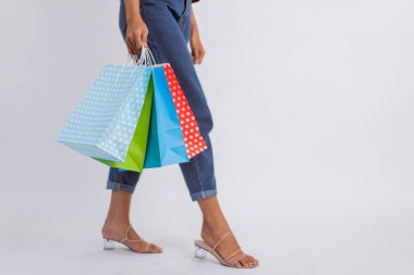 woman legs standing with heels while bring the shopping bags on isolated background