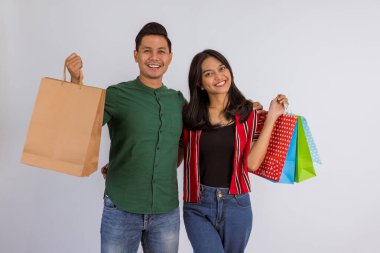 happy asian couple embrace each other while bring the shopping bags on isolated background