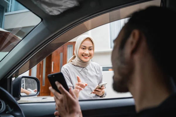asian hijab woman orders online transportation with her mobile app when the driver arrives