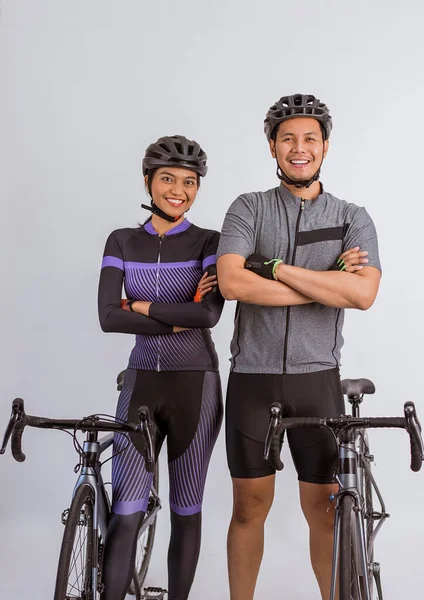 asian couple in cycling outfit standing with handcrossed beside their bicycles on isolated background