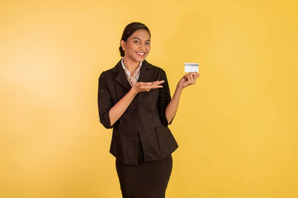 asian woman in formal outfit showing and pointing on the blank card on orange isolated background