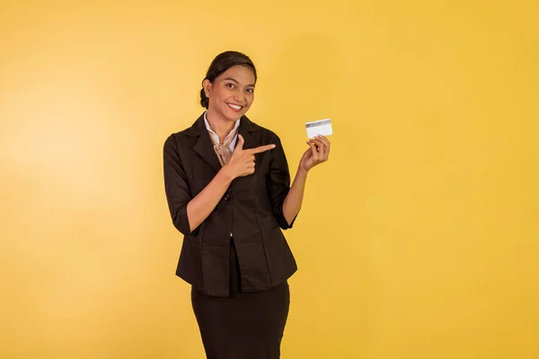 asian woman in formal outfit standing with pointed finger on the blank card on orange isolated background