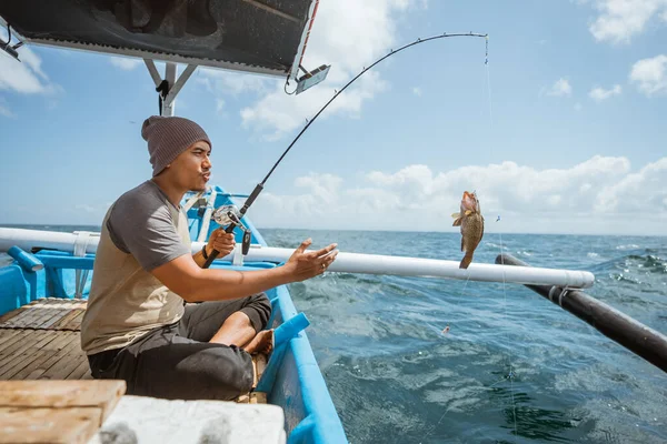 Asian Angler Pulls Rod Catches Fish Sea — Stock Photo, Image