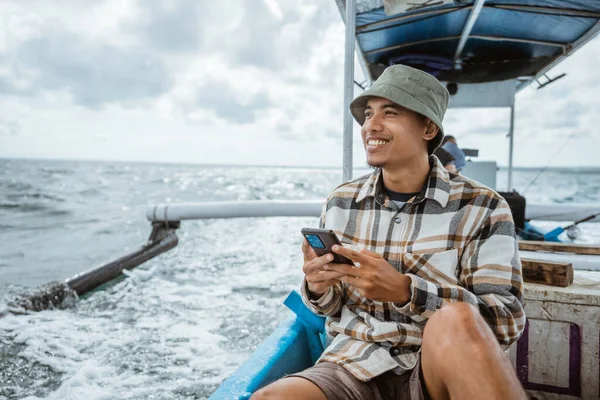 Asian Angler Sits Relaxed While Using Smartphone Fishing Boat — Stockfoto
