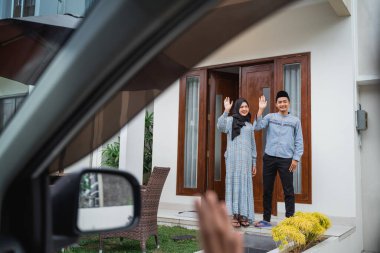 view from the car window young Asian Muslim couple waving to guests in the car